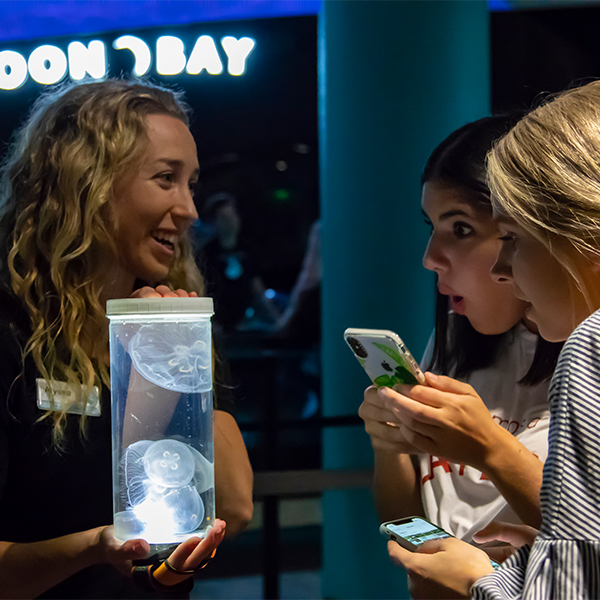 women_looking_at_moon_jellies_in_a_jar