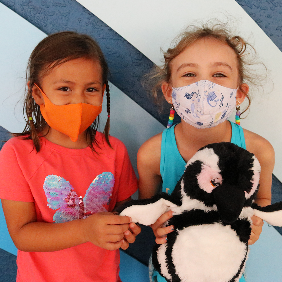 Two children holding a penguin plush toy