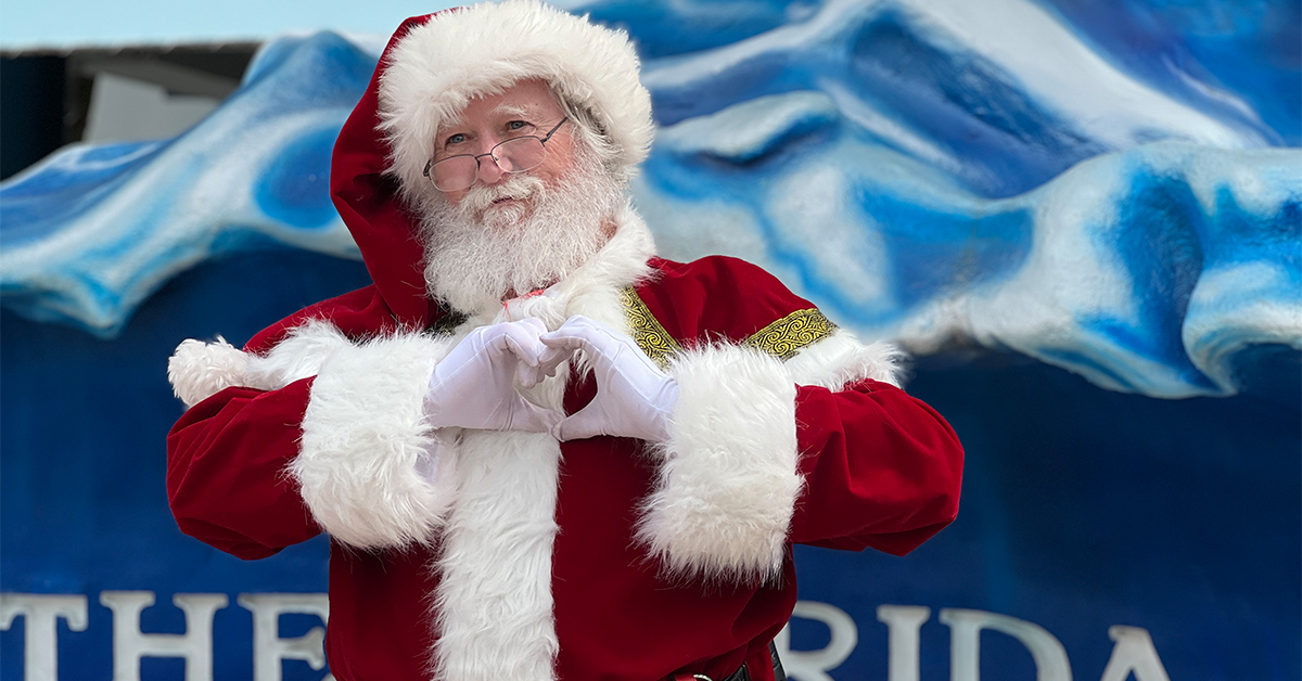 santa holding his hands in the shape of a heart outside the florida aquarium