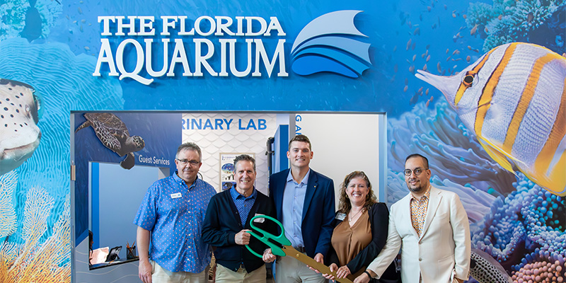 the florida aquarium leadership team holds ribbon cutting scissors