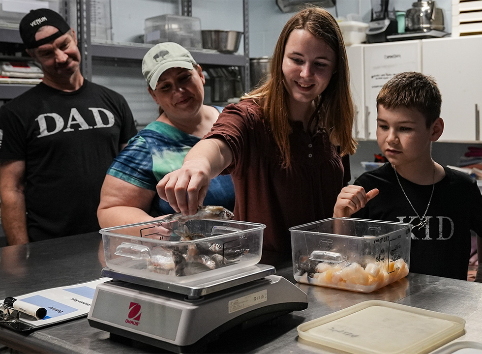 mom, dad, daughter, son, in commissary weighing fish to feed stingrays