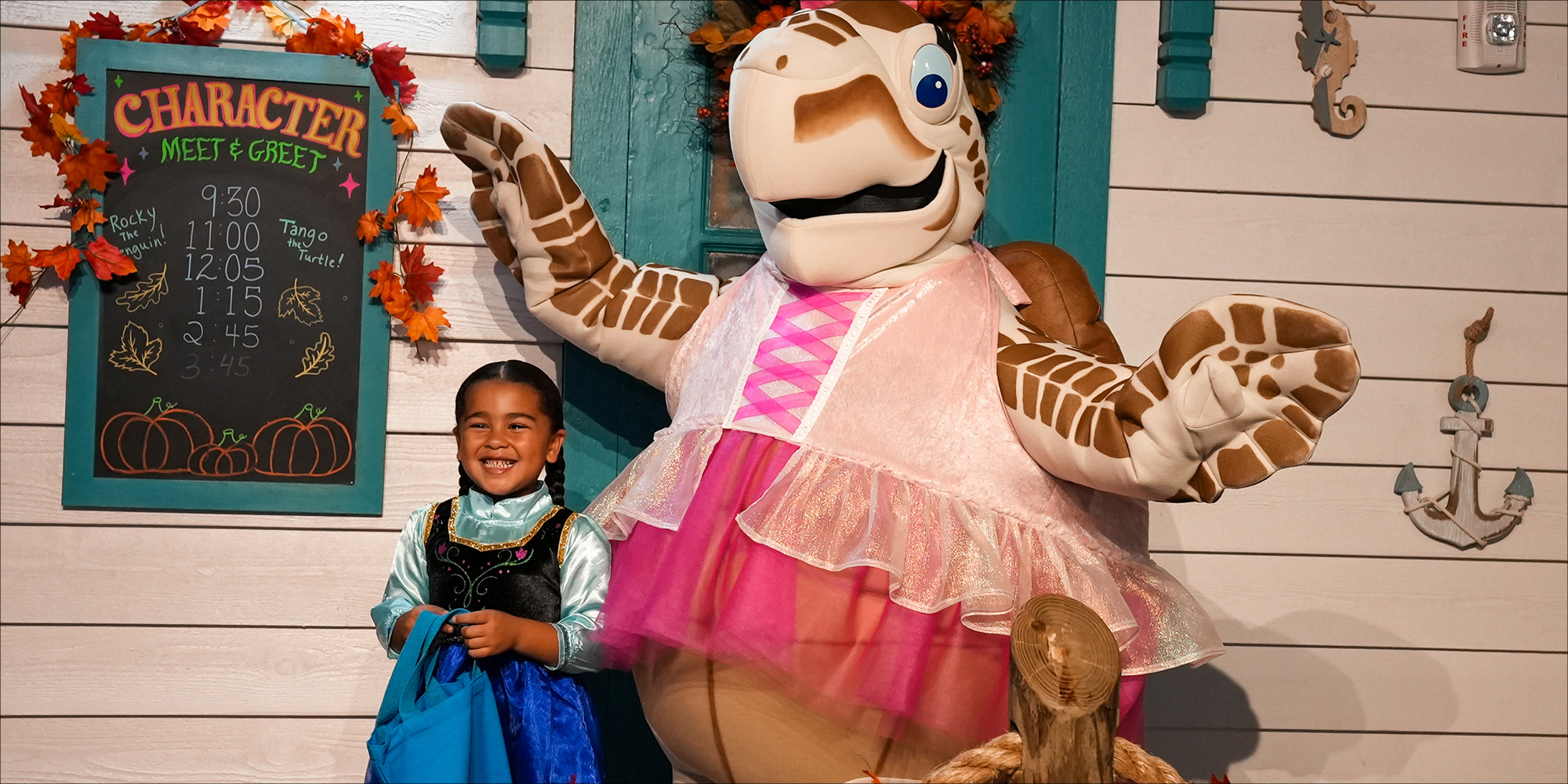 Tango taking a photo with a little girl in their halloween costumes at Guppyween at The Florida Aquarium.