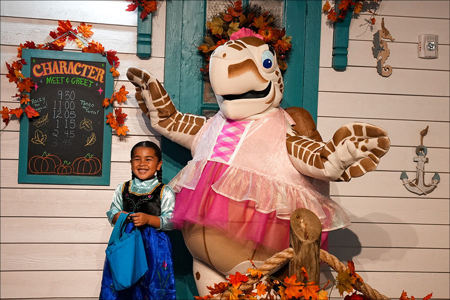 Tango taking a photo with a little girl in their halloween costumes at Guppyween at The Florida Aquarium.