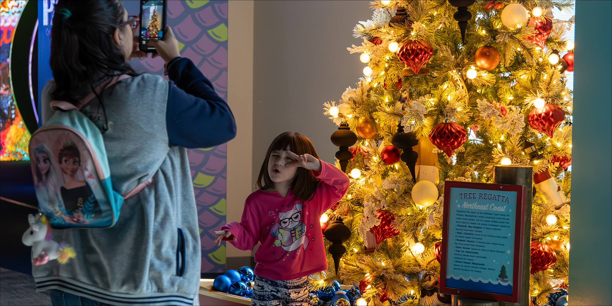 Little Girl at yuletides taking a photo with a tree