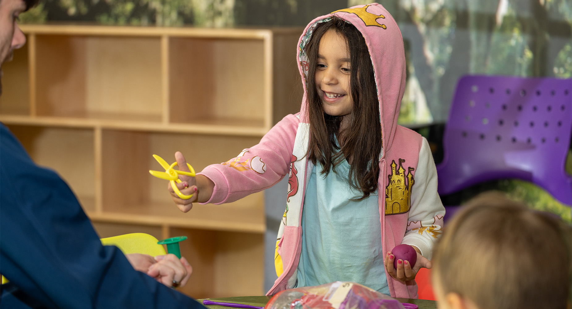 AquaTots-girl-with-big-smile-holding-plastic-scissors