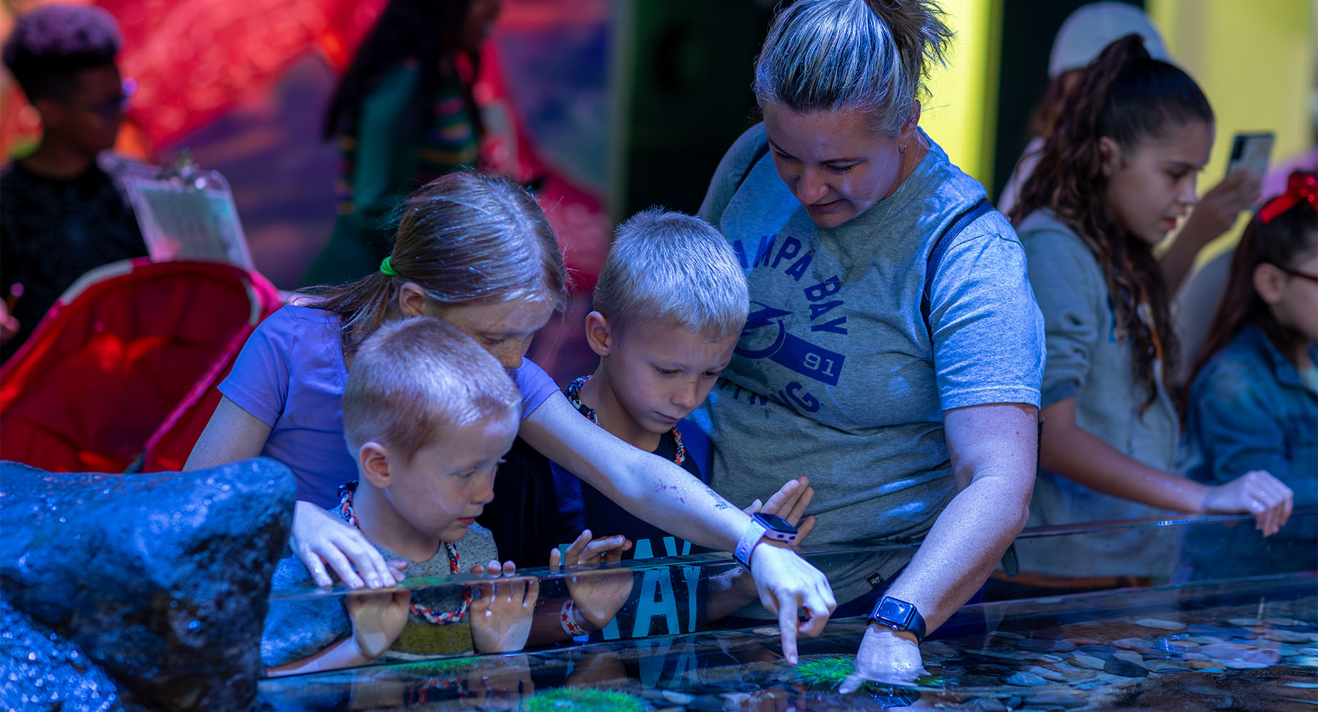 two young boys, one young girl, and mom at The Tide Pool habitat in The Florida Aquarium tampa FL