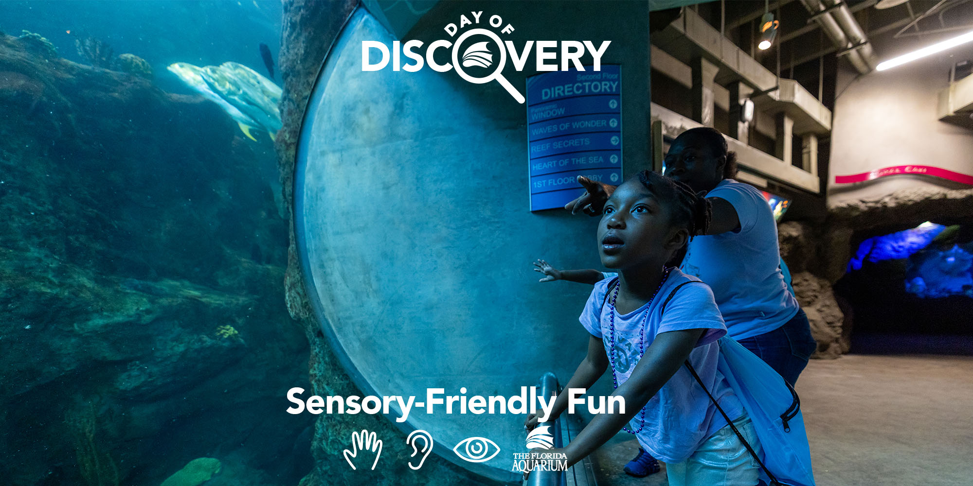 Young girl looking in awe at animals in coral tunnel with her mom during Day of Discovery at The Florida Aquarium