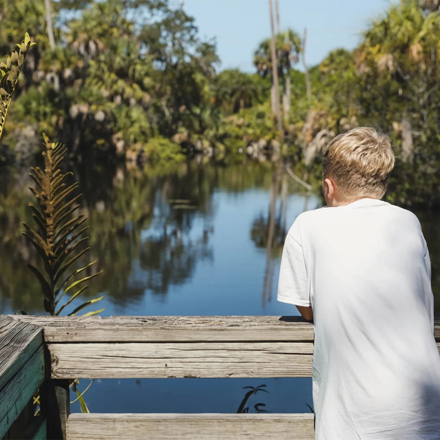 boy looking out at lake and trees